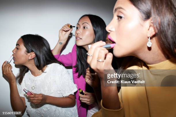 women applying make-up while standing together - friends women makeup stockfoto's en -beelden