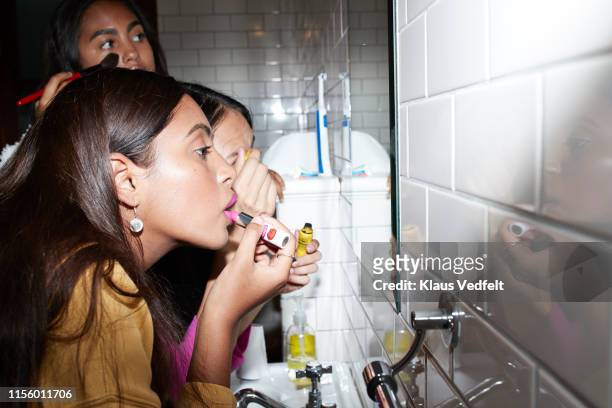 friends applying make-up while looking at mirror - bad relationship stock-fotos und bilder
