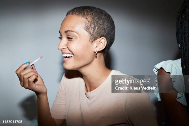 smiling woman applying lip gloss at home - shiny lips stock pictures, royalty-free photos & images