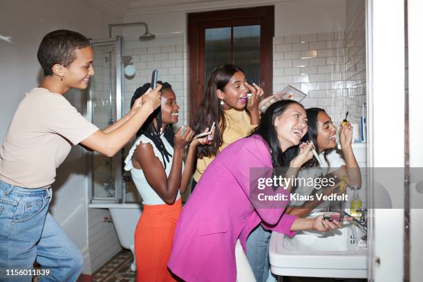 smiling woman photographing friends doing make-up - mode femme photos et images de collection