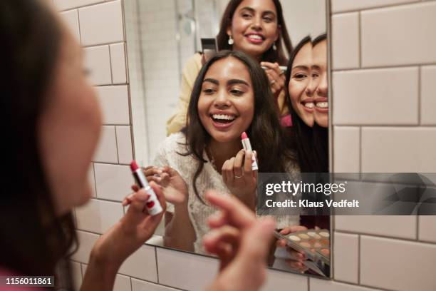 smiling friends with lipstick looking at mirror - friend bathroom photos et images de collection