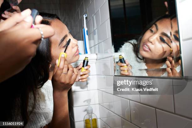 woman applying mascara while looking at mirror - mascaras 個照片及圖片檔