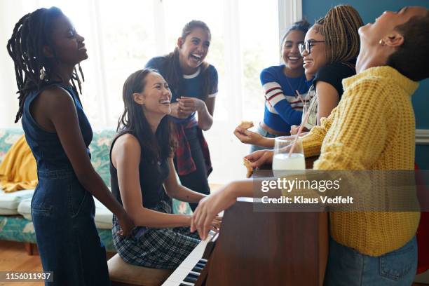 woman playing piano for cheerful friends at home - woman playing squash stock pictures, royalty-free photos & images