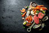 Raw tuna steak and seafood on wooden tray.