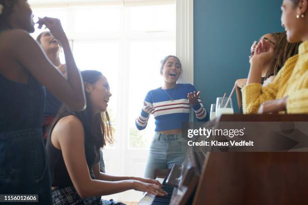 female friends singing while woman playing piano - woman playing squash stock pictures, royalty-free photos & images