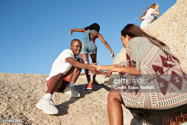 Man assisting friend in climbing rock