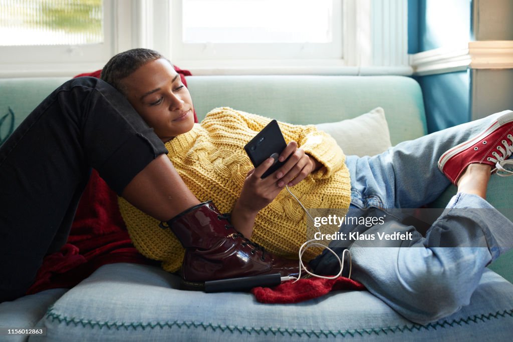 Woman using phone while leaning on friend's leg