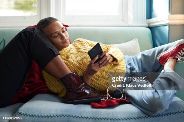 Woman using phone while leaning on friend's leg
