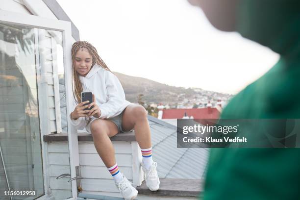 woman photographing friend while sitting on terrace - sims stock-fotos und bilder