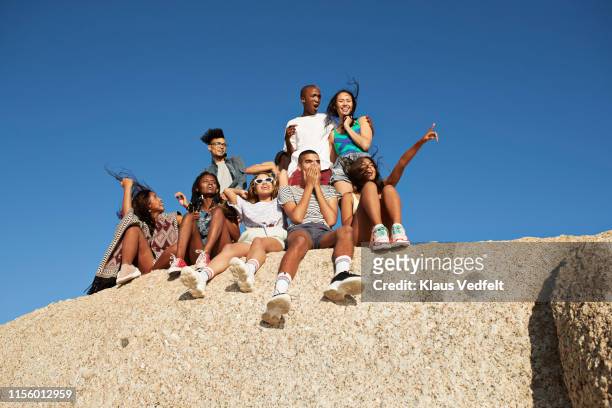 cheerful friends sitting together on rock - generation z group stock pictures, royalty-free photos & images