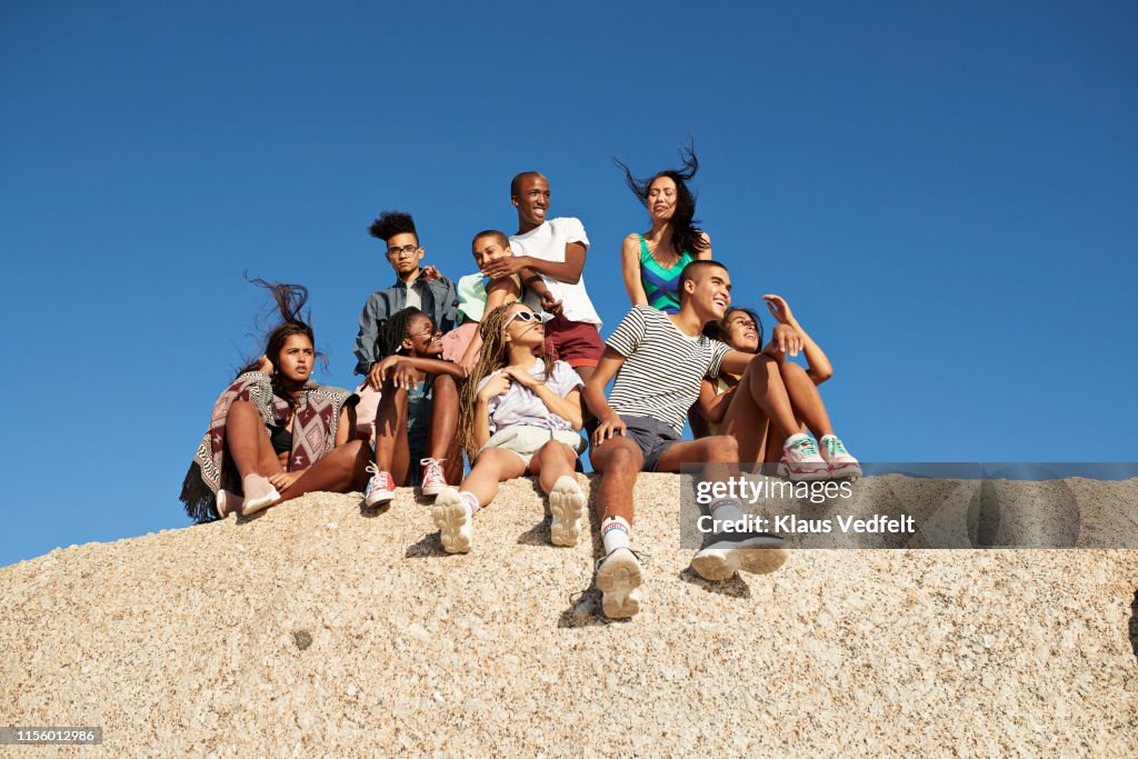 Multi-ethnic friends sitting together on rock