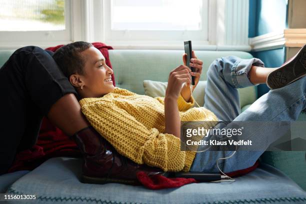 woman messaging on phone while leaning on friend - comodità foto e immagini stock