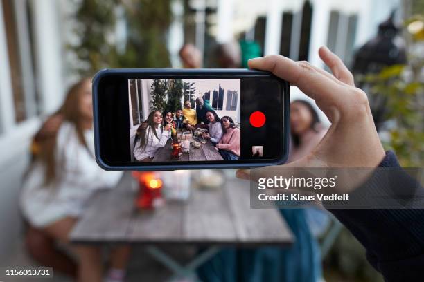 friends sitting at table seen on smart phone screen - smartphone pov stockfoto's en -beelden