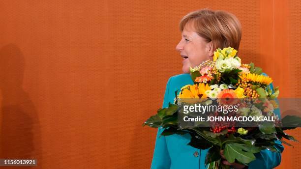 German Chancellor Angela Merkel holds the flowers that she will offer to Defence Minister during the weekly cabinet meeting on July 17, 2019 at the...