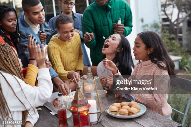 cheerful friends enjoying food at table - pizza toss foto e immagini stock