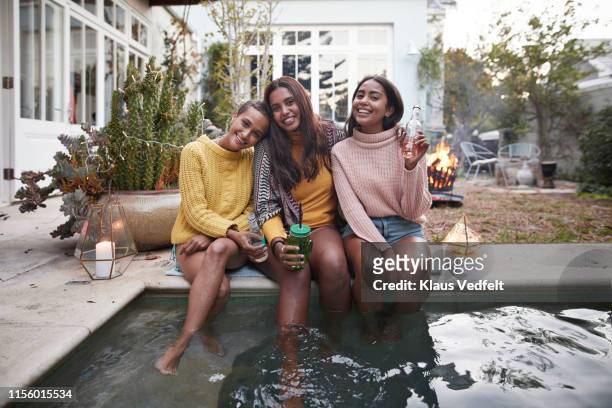 portrait of happy friends with drinks at poolside - drinkwater kante stock-fotos und bilder