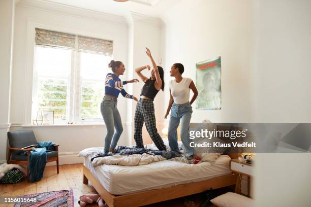 Female friends enjoying while dancing on bed