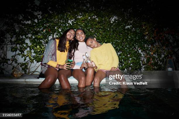 portrait of female friends resting at poolside - pool party night stock pictures, royalty-free photos & images