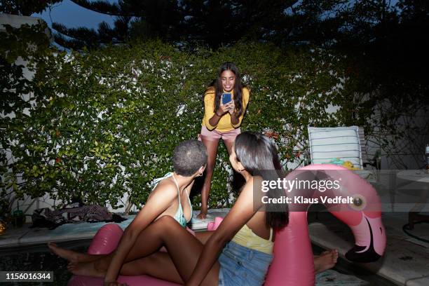 woman photographing friends on inflatable raft - pool party night stock pictures, royalty-free photos & images