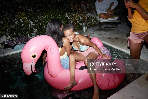 cheerful female friends floating on raft in pool - fiesta de piscina fotografías e imágenes de stock
