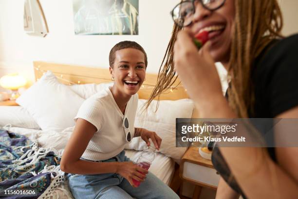 woman looking at female friend eating strawberry - generation z food stock pictures, royalty-free photos & images