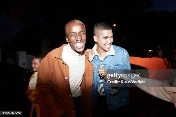 smiling men enjoying with friends at night - man in denim jacket stock pictures, royalty-free photos & images
