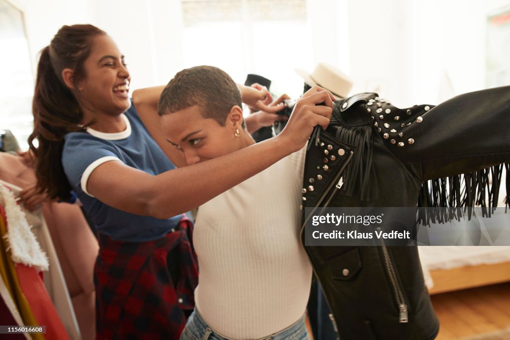 Woman helping friend wearing black leather jacket
