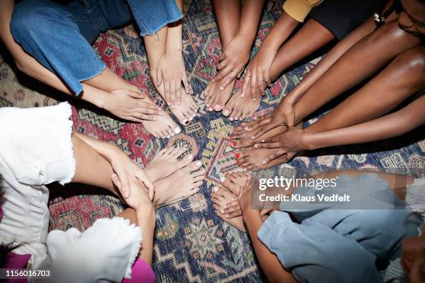 multi-ethnic friends sitting together in circle on carpet - toenail stock pictures, royalty-free photos & images
