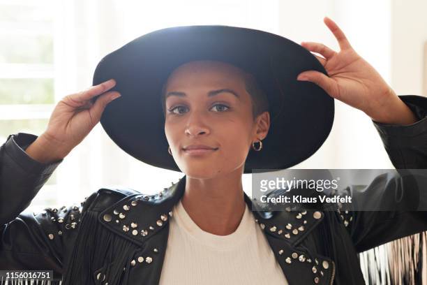 portrait of confident young woman holding hat - fashion millinery woman stock-fotos und bilder