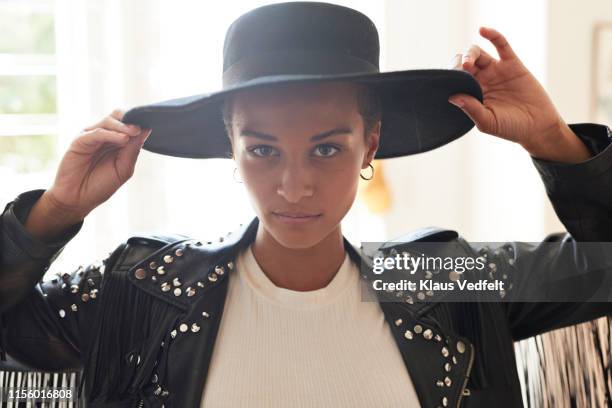 portrait of confident young woman holding black hat - embellished jacket stock pictures, royalty-free photos & images