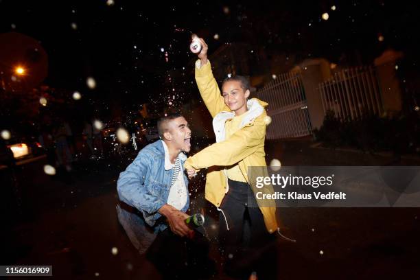 happy man and woman splashing drink - veste jaune photos et images de collection