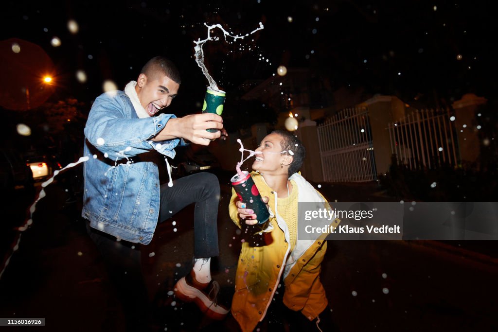 Cheerful male and female splashing drink