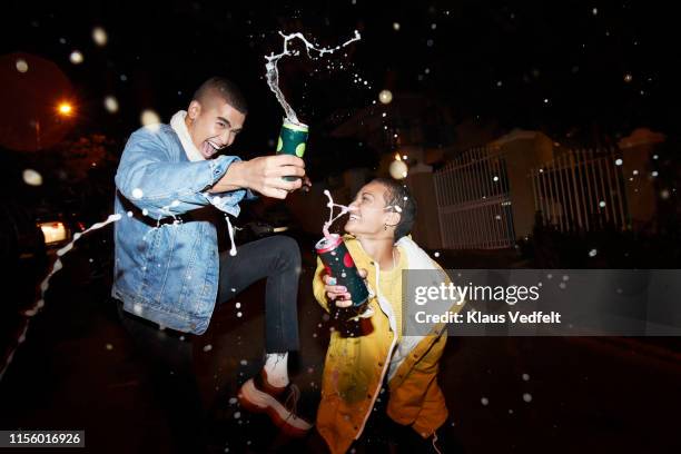 cheerful male and female splashing drink - bier stockfoto's en -beelden