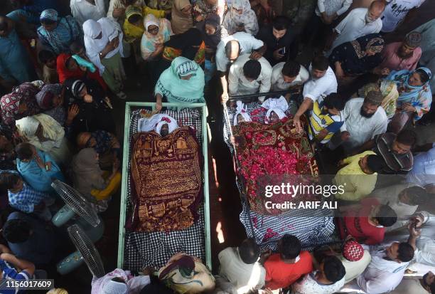 Graphic content / Pakistani mourners gather around the bodies of family members who died when the roof of their house collapsed following heavy...