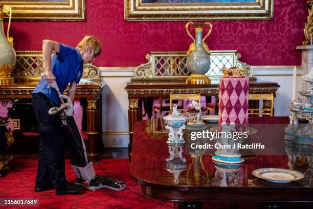 Palace employee vacuums next to a recreation of a royal Victorian dinner in the State Dining Room at Buckingham Palace on July 17, 2019 in London,...