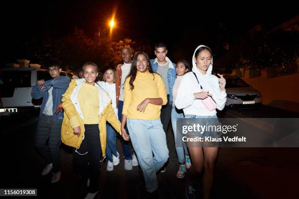 multi-ethnic friends walking on street in city at night - night of fashion for a cause to benefit stomp out bullying stockfoto's en -beelden