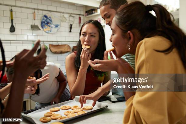 friends eating fresh cookies in kitchen at home - indulgence photos et images de collection