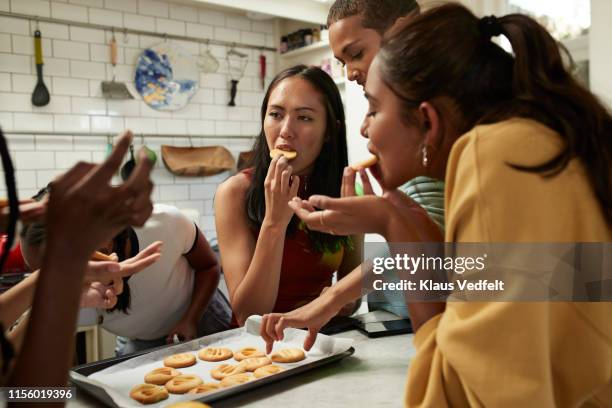 friends eating fresh cookies in kitchen at home - parceiro de apartamento - fotografias e filmes do acervo