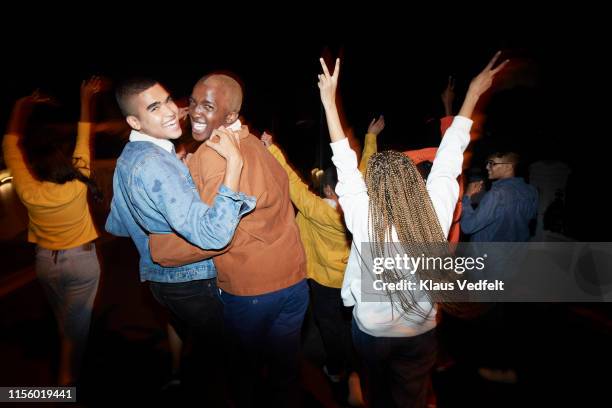 cheerful men dancing with friends at night - night out stock pictures, royalty-free photos & images