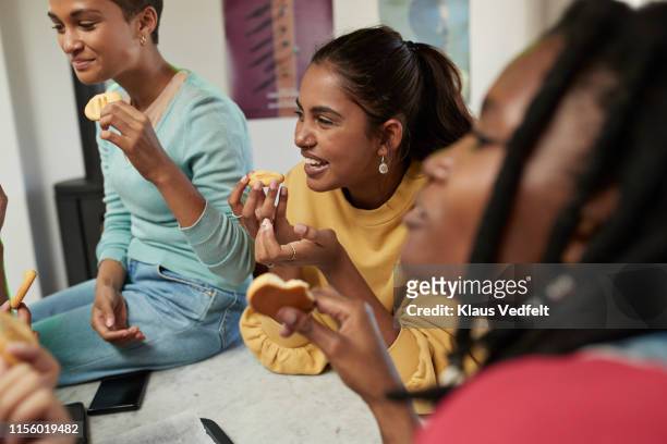 smiling women enjoying cookies at home - biscuit ストックフォトと画像