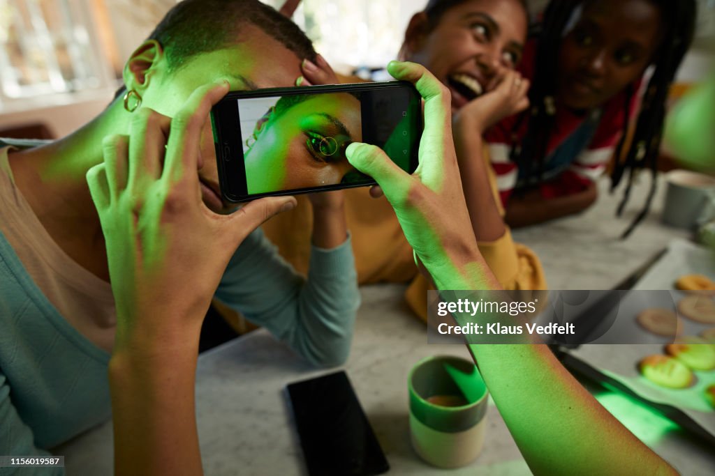 Woman photographing female friend's eye on phone