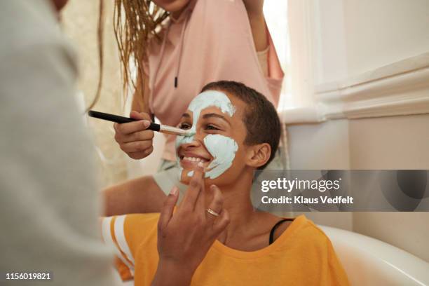 woman enjoying female friends applying cream on face - friends clean stock pictures, royalty-free photos & images