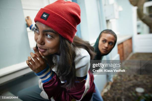 woman with friend gesturing finger on lips - couvert stock pictures, royalty-free photos & images