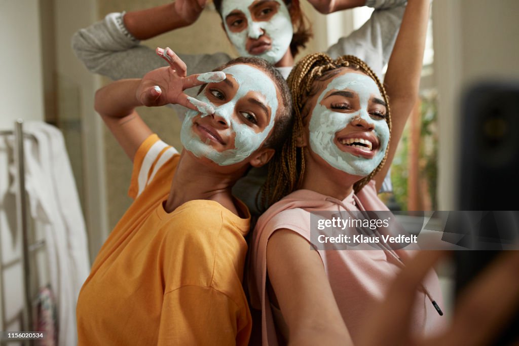 Happy woman taking selfie with friends wearing cream