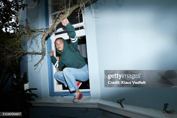 woman sneaking out of house window - contact list stock-fotos und bilder