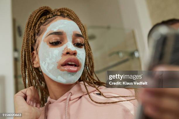 woman with cream on face using smart phone - pink vanity stock pictures, royalty-free photos & images