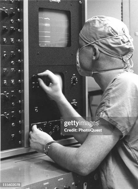 An unidentified doctor makes adjustments to a cardiopulmonary bypass pumps during a surgery, Baltimore, Maryland, 1959. The perfusionist specializes...