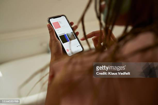 young woman using smart phone in bathroom - mp3 player stock pictures, royalty-free photos & images