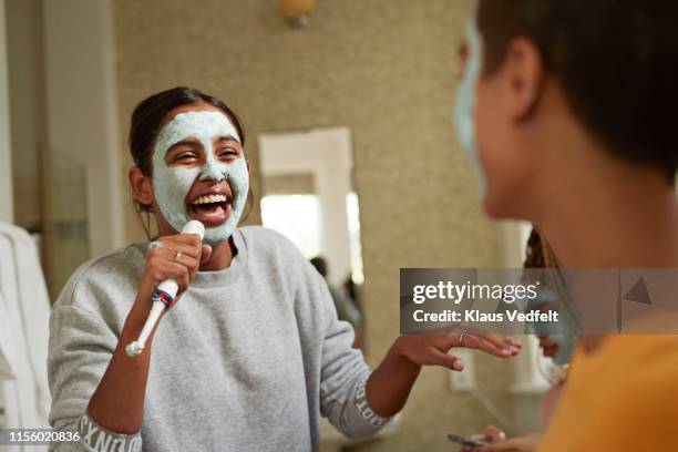 cheerful woman singing in front of female friend - elektrische zahnbürste stock-fotos und bilder