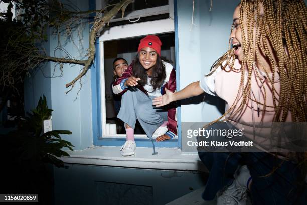woman assisting friends while sneaking out - leap day stockfoto's en -beelden